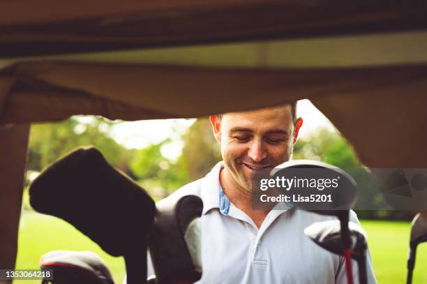 happy golfer chooses his golf club from a golf bag - golf caddy stockfoto's en -beelden