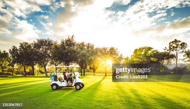 father and daughter drive golf cart on scenic idyllic golf course playing a round of golf with active family - golf cart stock pictures, royalty-free photos & images