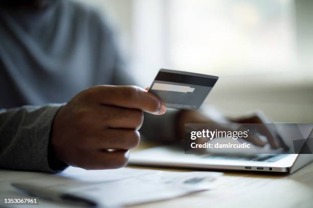 hombre usando tarjeta de crédito y computadora portátil para compras en línea - pagar fotografías e imágenes de stock