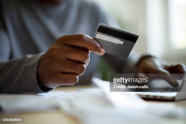 man using a credit card to pay bills - african american money stock pictures, royalty-free photos & images