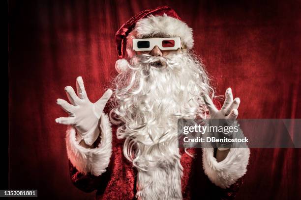 person dressed as santa claus, in profile, with retro 3d glasses, gesturing with hands, on red vintage background. christmas, santa claus, gifts, december and celebrations concept. - ugly santa stockfoto's en -beelden