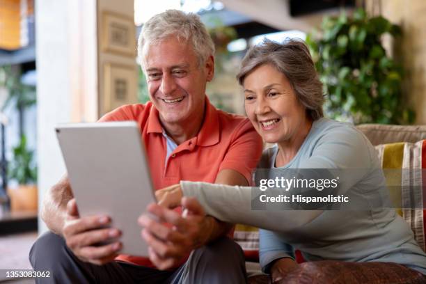 happy senior couple looking at social media on a tablet computer - 隔離 狀況 個照片及圖片檔