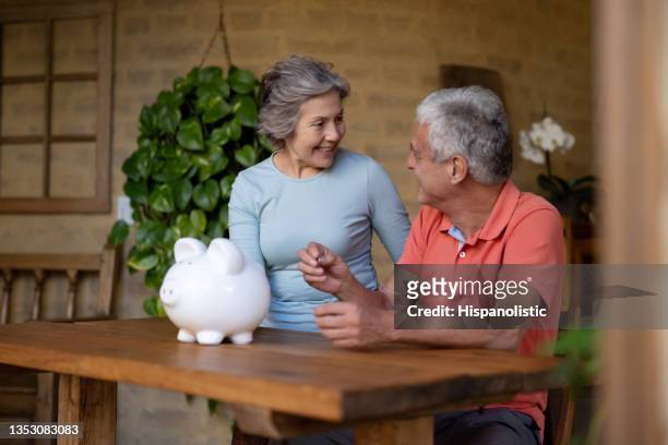 couple of senior adults saving money in a piggybank - retirement income stock pictures, royalty-free photos & images
