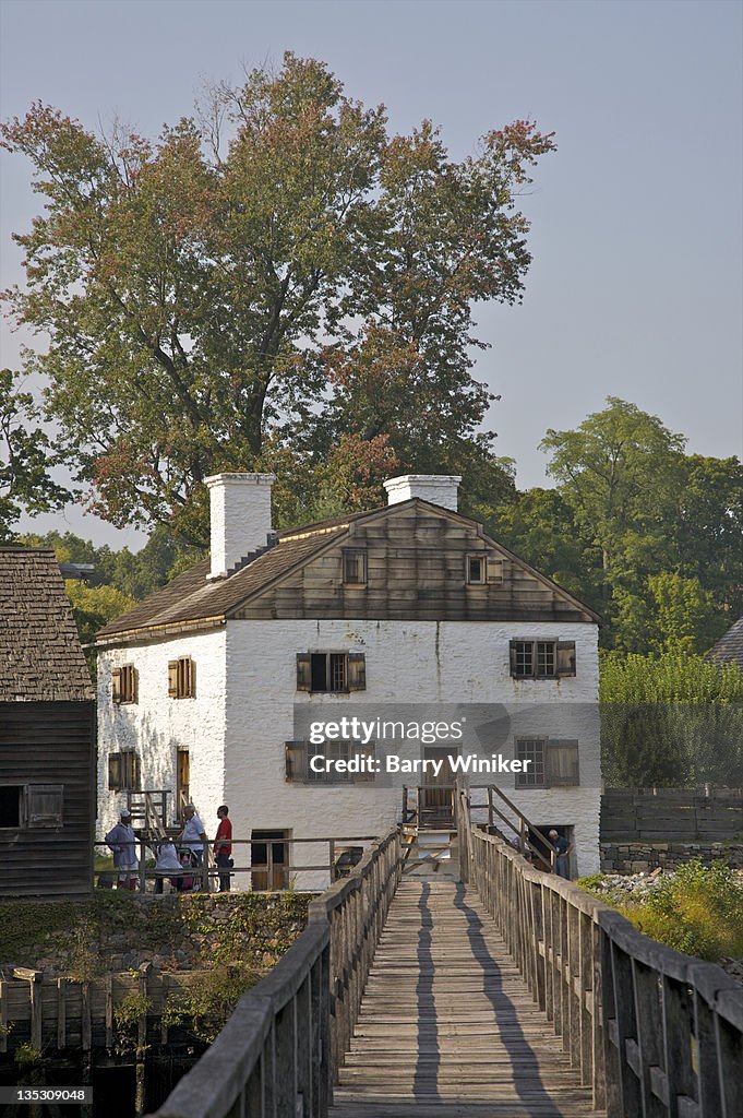 Wood bridge leading to white building.