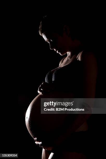 pregnant woman in lingerie holding stomach - tienerzwangerschap stockfoto's en -beelden