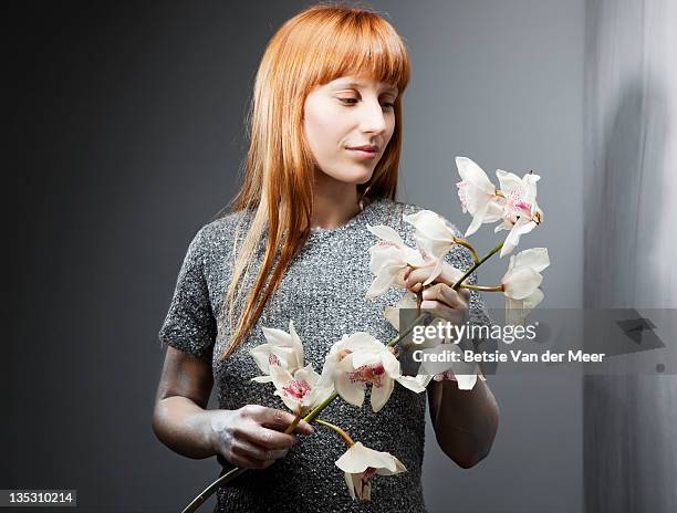 woman holding stem of orchids. - long stem flowers stock pictures, royalty-free photos & images