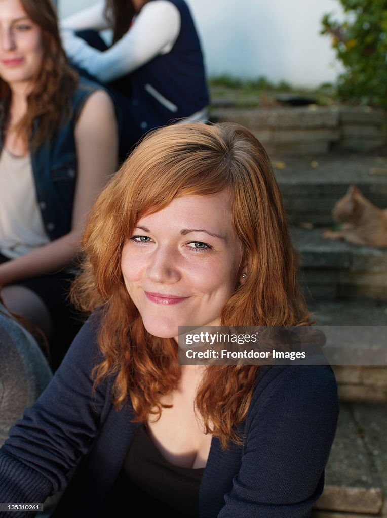 Redhead young woman sitting with group of friends