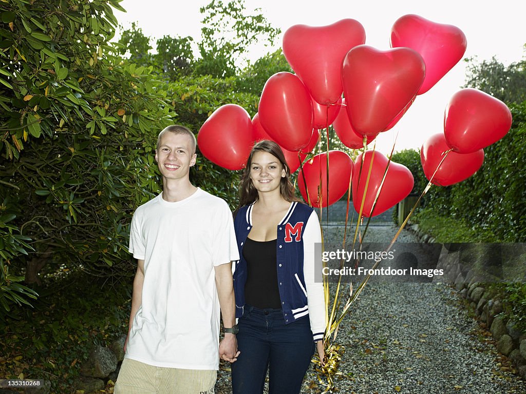 Two teens holding a lot of heart shaped balloon