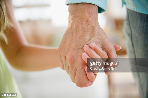 grandma and granddaughter holding hands, close up - kid hand holding stock-fotos und bilder