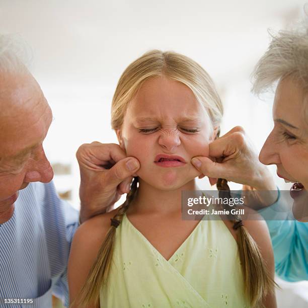 grandparents pinching granddaughter's cheeks - pressure photos et images de collection