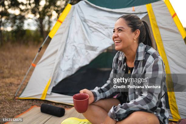 woman drinking coffee at camp in forest - camping equipment stock pictures, royalty-free photos & images