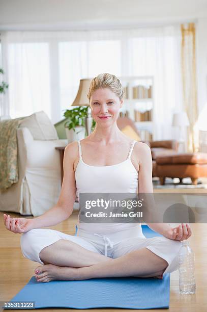 woman doing yoga at home - schneidersitz stock-fotos und bilder