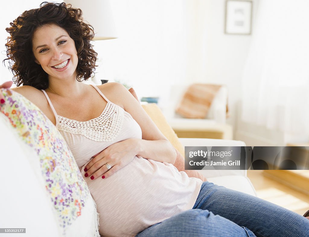 Pregnant woman on couch, smiling