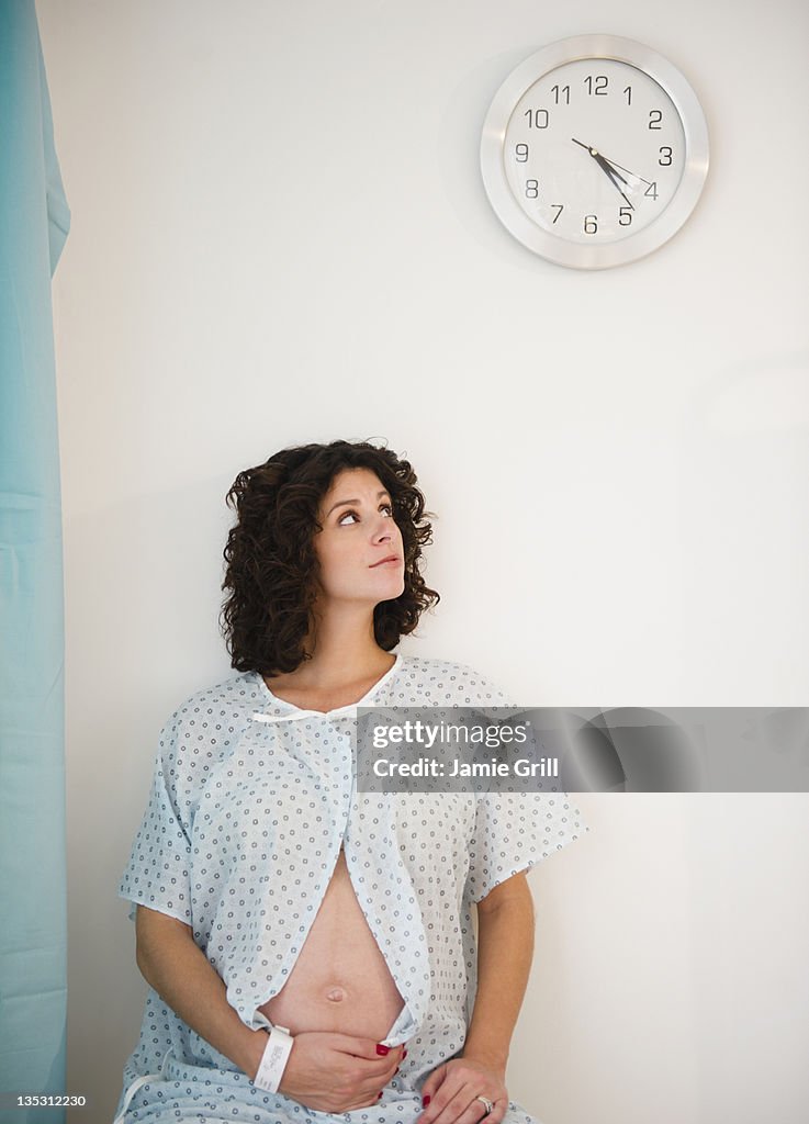 Pregnant woman in hospital looking at clock