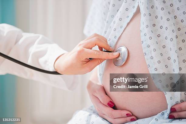 doctor with stethoscope on pregnant woman's belly - auscultation woman stockfoto's en -beelden