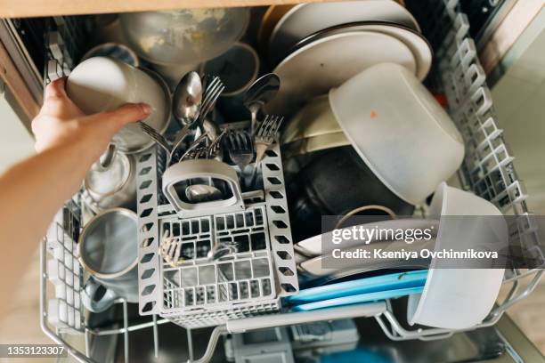 putting dirty plates in the dishwasher after dinner - loading dishwasher stock pictures, royalty-free photos & images