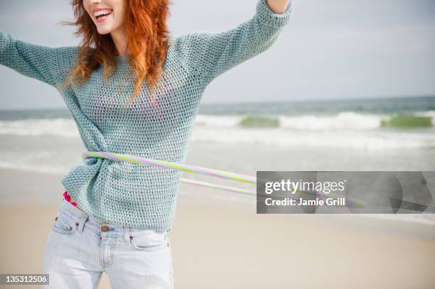 young woman hula hooping on beach - middle age imagens e fotografias de stock