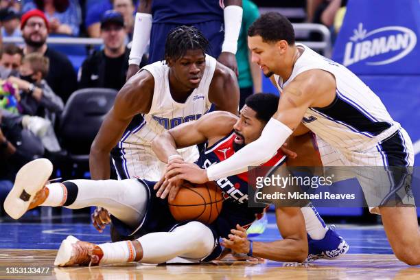 Spencer Dinwiddie of the Washington Wizards battles for a loose ball with Mo Bamba and Jalen Suggs of the Orlando Magic during the first half at...
