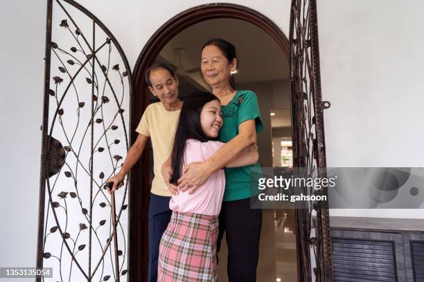 teenager girl and senior woman embracing at the front door - family smiling at front door stock pictures, royalty-free photos & images