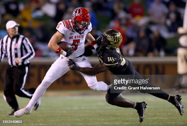 Malik Mustapha of the Wake Forest Demon Deacons tackles Thayer Thomas of the North Carolina State Wolfpack during the first half of their game at...
