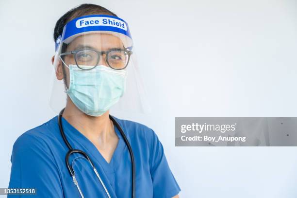 portrait of asian male healthcare worker in medical scrubs with mask and face shiled, ready to work in hospital. - face shield 個照片及圖片檔