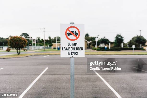 do not leave children in cars sign in an empty suburban carpark - generic safety sign stock pictures, royalty-free photos & images