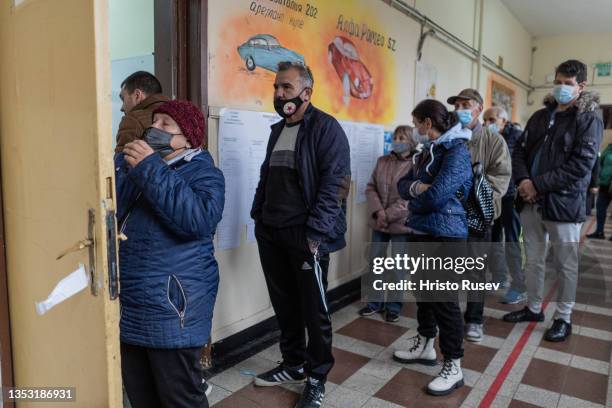 People queue in front of a polling station to cast their vote, during the presidential and parliamentary elections on November 14, 2021 in Sofia,...