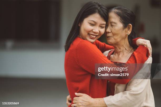 eine asiatische großmutter umarmt ihre enkelin mit liebe - alter wunsch fürs neue jahr stock-fotos und bilder