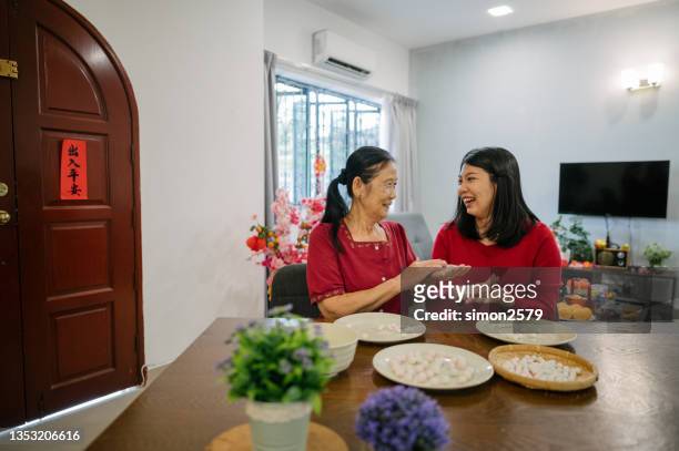 an asian grandmother and her granddaughter preparing making glutinous rice dumplings (tang yuan)  for chinese new year celebration - chinese prepare for lunar new year stock pictures, royalty-free photos & images