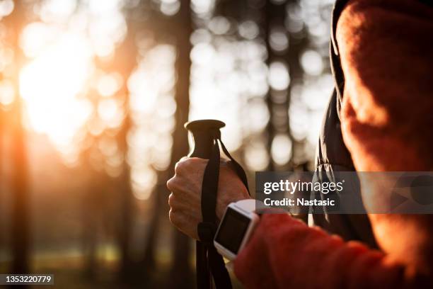 nicht wiederzuerkennen, ältere frau beim wandern mit smartwatch - wanderstock stock-fotos und bilder