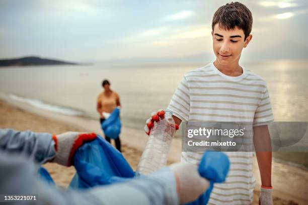 freiwillige sammeln plastikmüll auf und reinigen den strand - volunteer beach stock-fotos und bilder