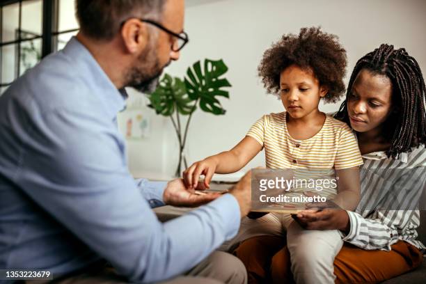 mother having a therapy session for her daughter with male psychologist - psychotherapy stock pictures, royalty-free photos & images
