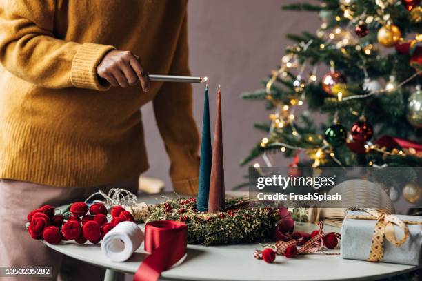anonymous woman lighting christmas candles - lighter stockfoto's en -beelden