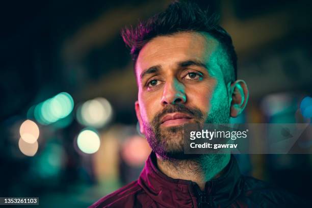 young man looks away at night in the city street. - teal portrait stock pictures, royalty-free photos & images