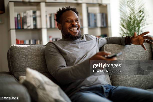 cheerful man watching tv in living room - alter tv stock pictures, royalty-free photos & images