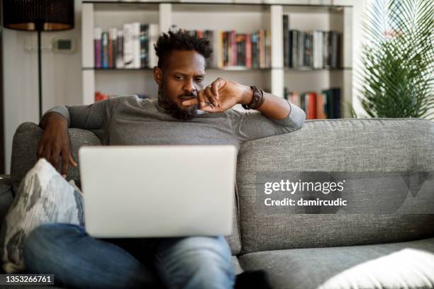 young man watching movie on laptop at home - confuso imagens e fotografias de stock