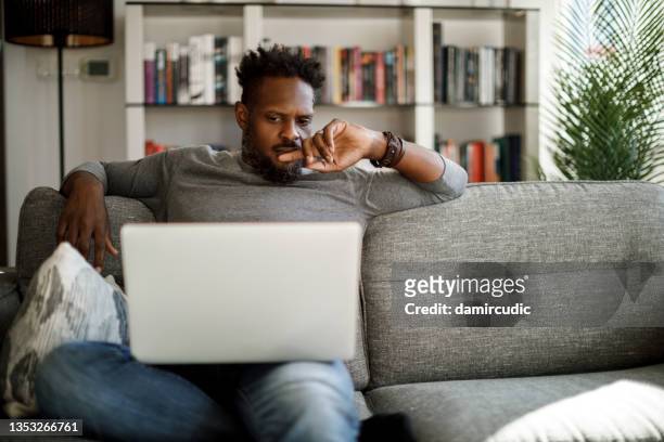 young man watching movie on laptop at home - confusion bildbanksfoton och bilder