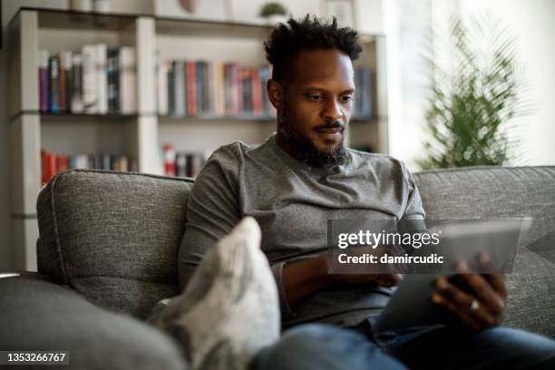 young man using digital tablet at home - african american watching tv stock pictures, royalty-free photos & images