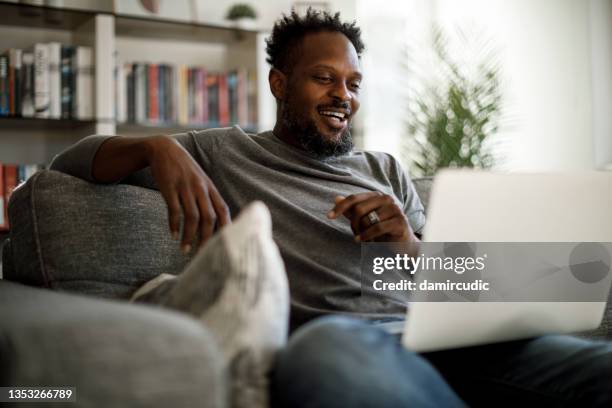 young smiling man watching movie on laptop at home - movie meets media stockfoto's en -beelden