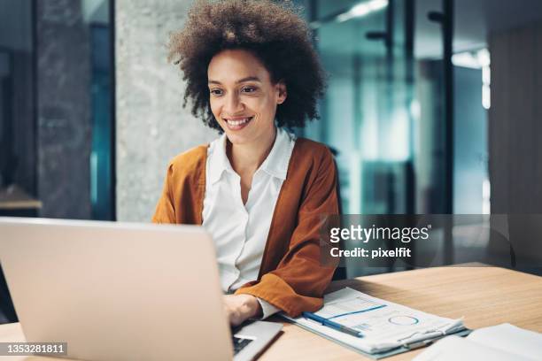 businesswoman using laptop - looking at computer smiling stockfoto's en -beelden