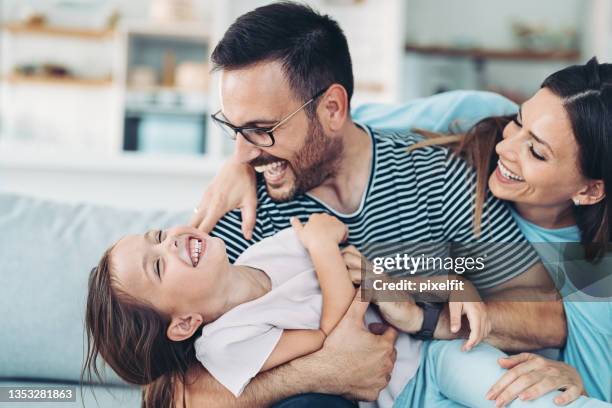 familia feliz con una niña divirtiéndose en casa - familia en casa fotografías e imágenes de stock