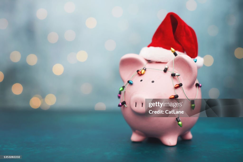 サンタハットを身に着けているピンクの貯金箱とクリスマス貯蓄の背景