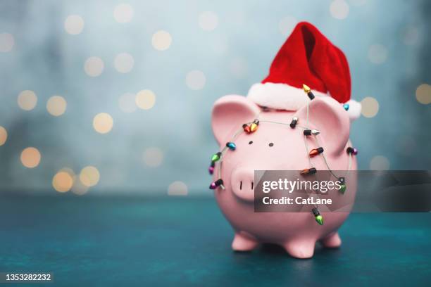 christmas savings background with pink piggy bank wearing santa hat - spaarvarken stockfoto's en -beelden