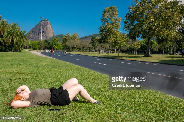 woman listens to music lying on the lawn in the park - flamengo park stock pictures, royalty-free photos & images