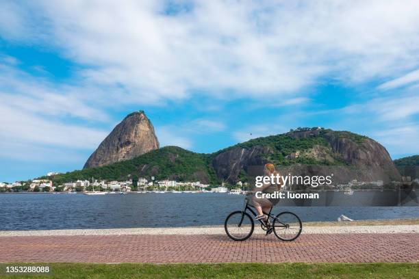 woman rides a bicycle with sugarloaf as a background - sugar loaf bildbanksfoton och bilder