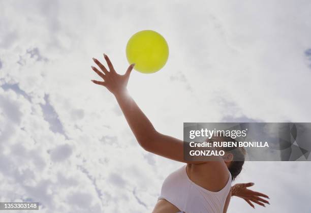 caucasian female playing beach volleyball looking at ball concentrate serving against cloudy sky. sport concept. - girls beach volleyball stock pictures, royalty-free photos & images