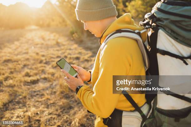 man explorer using a travel app or map on smartphone during his hike. - geocaching stock pictures, royalty-free photos & images