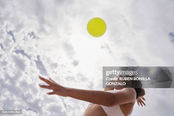 caucasian female playing beach volleyball looking at ball concentrate hitting the ball against cloudy sky. sport concept. - beachvolleyball stock-fotos und bilder