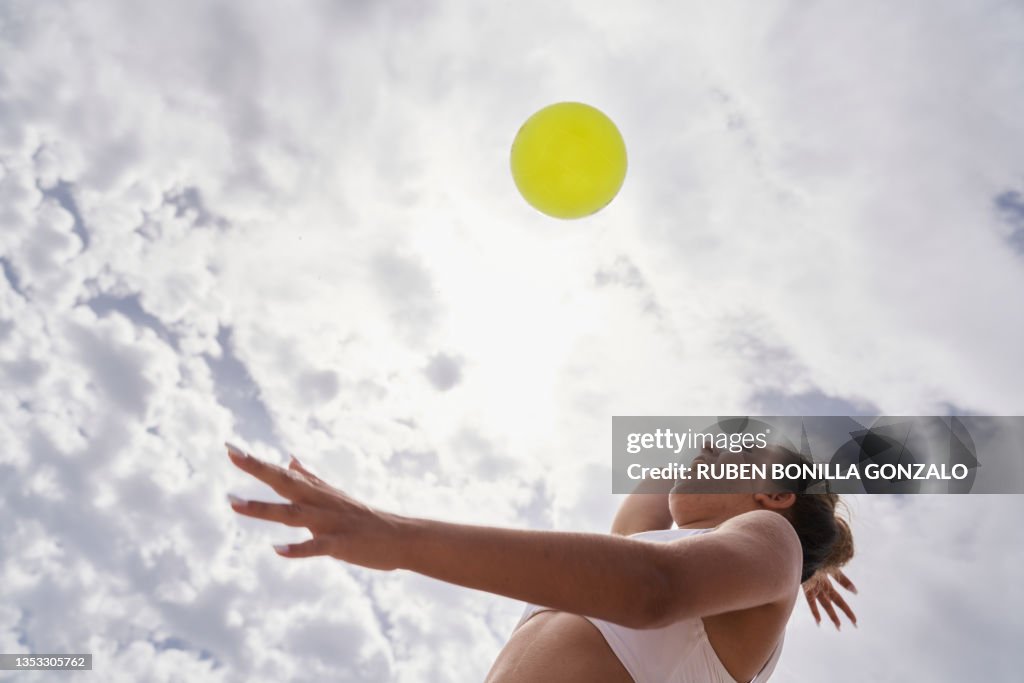 Caucasian Female playing beach volleyball looking at ball concentrate hitting the ball against cloudy sky. Sport concept.