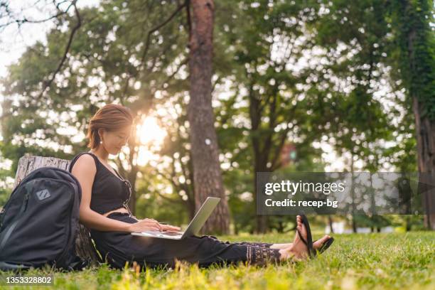 young woman relaxing in nature and using laptop - dramatic millennials stock pictures, royalty-free photos & images